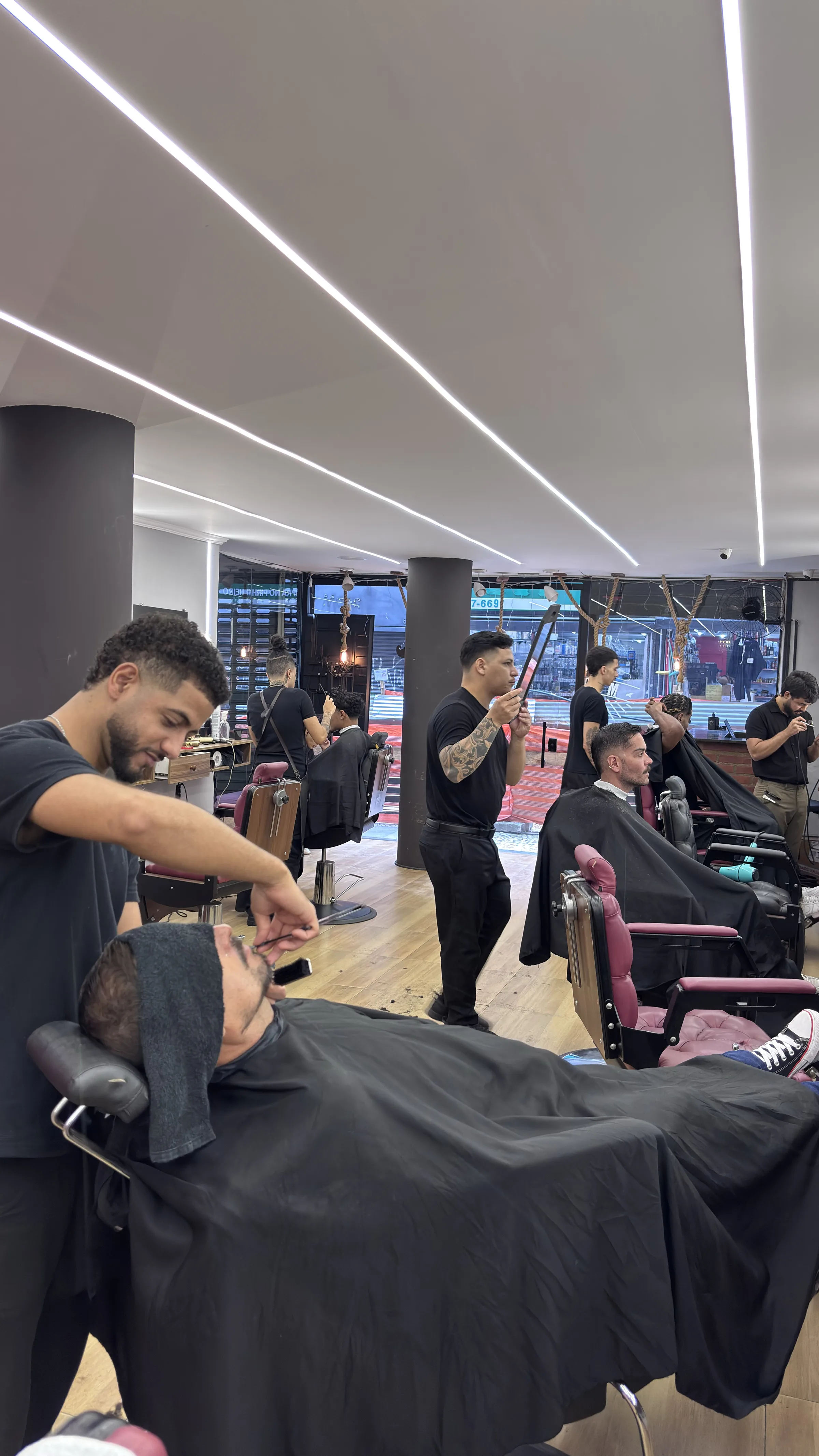 Barbeiro finalizando a barba de um cliente com toalha quente