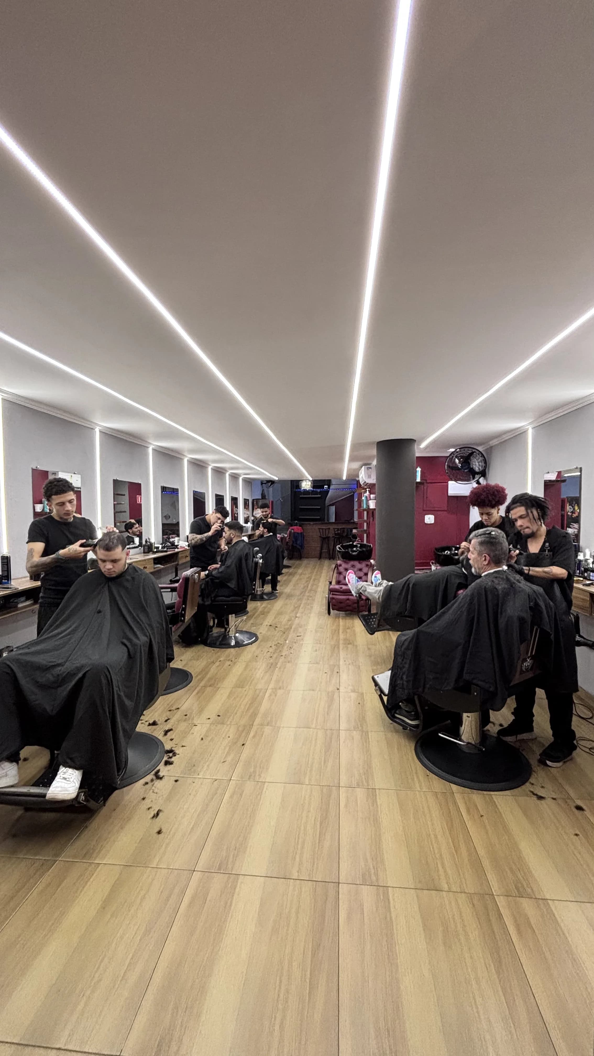 Barbeiros atendendo clientes em várias poltronas