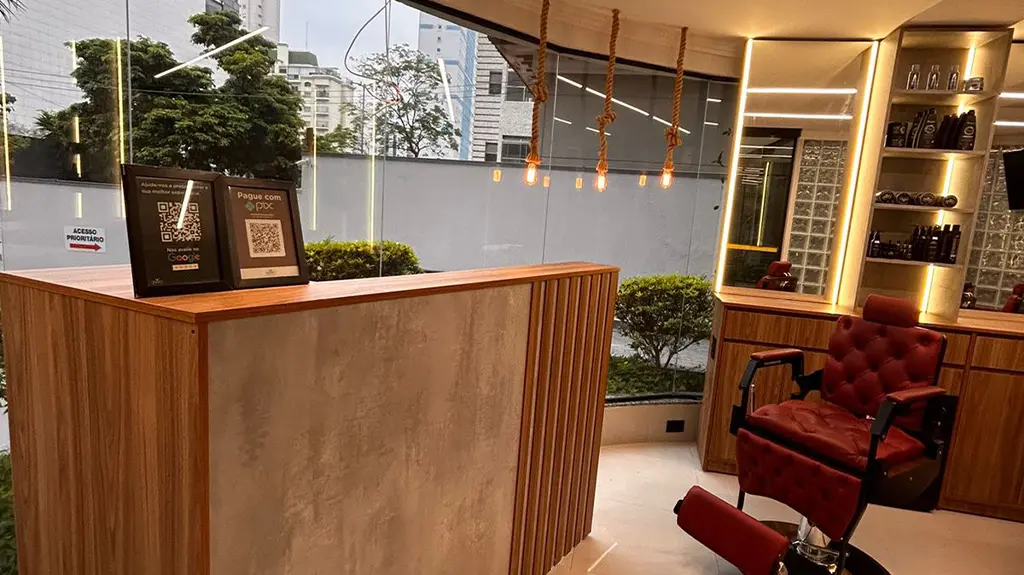 Recepção em madeira e dourado da Barbearia Marconi, unidade Jardins
